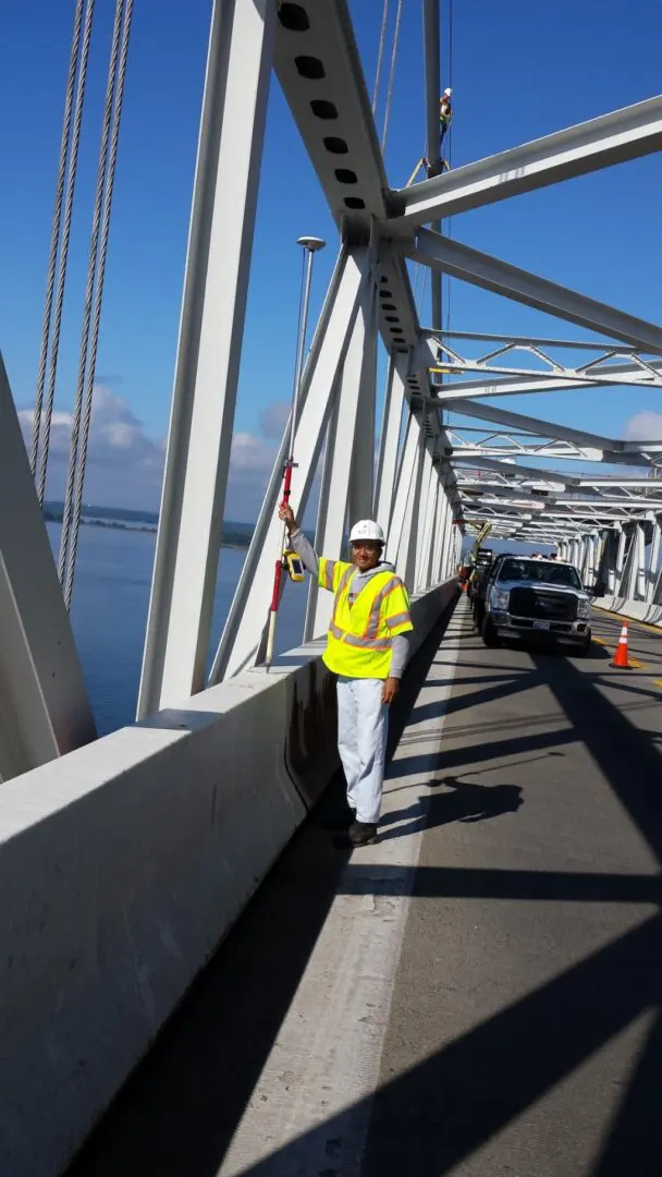 A man in yellow jacket standing on bridge.